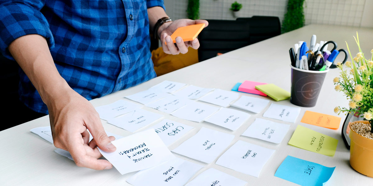 Designer standing at a table, sorting ideas out for an affinity map