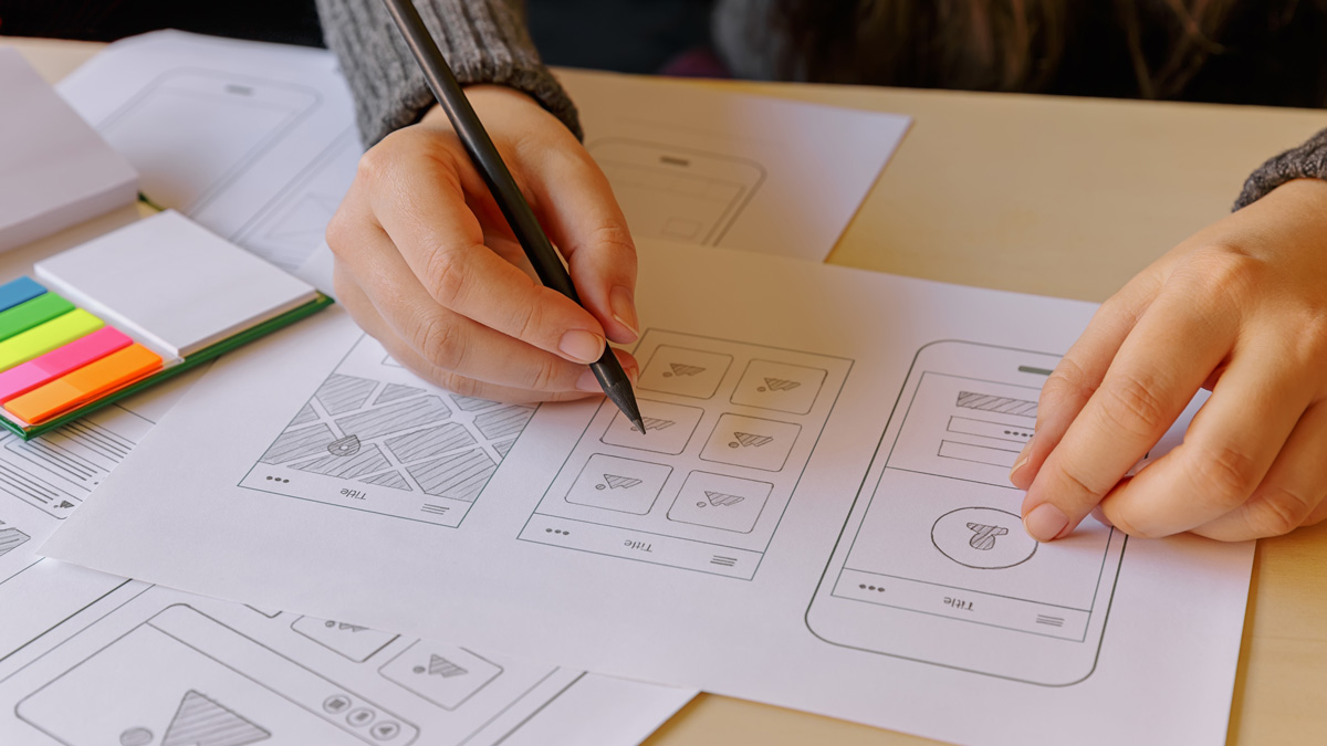 Close-up on a UX designer's hands, working on a set of paper prototypes