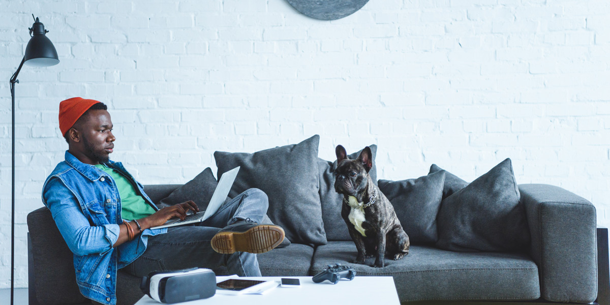 An aspiring UX designer sitting on a couch with his laptop and his dog