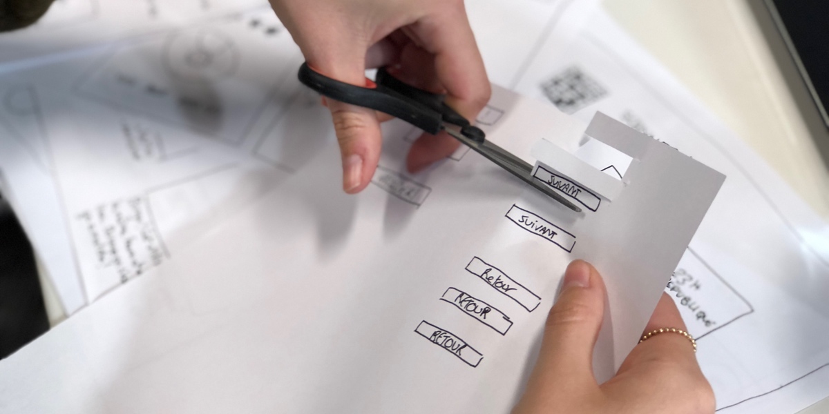 Close up of a UX designer's hands. They are cutting out elements for a paper prototype