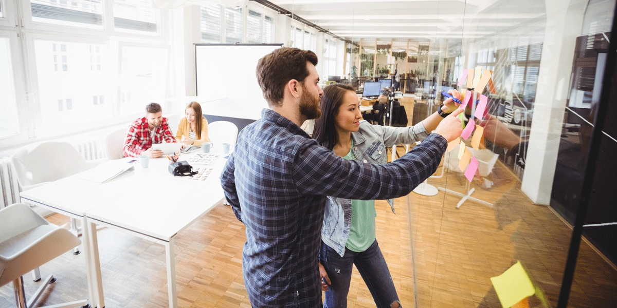 Two UX designers arranging Post-It notes on a wall